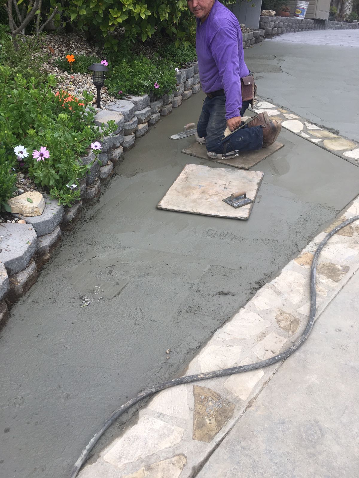 A person kneeling down on the ground with a tile