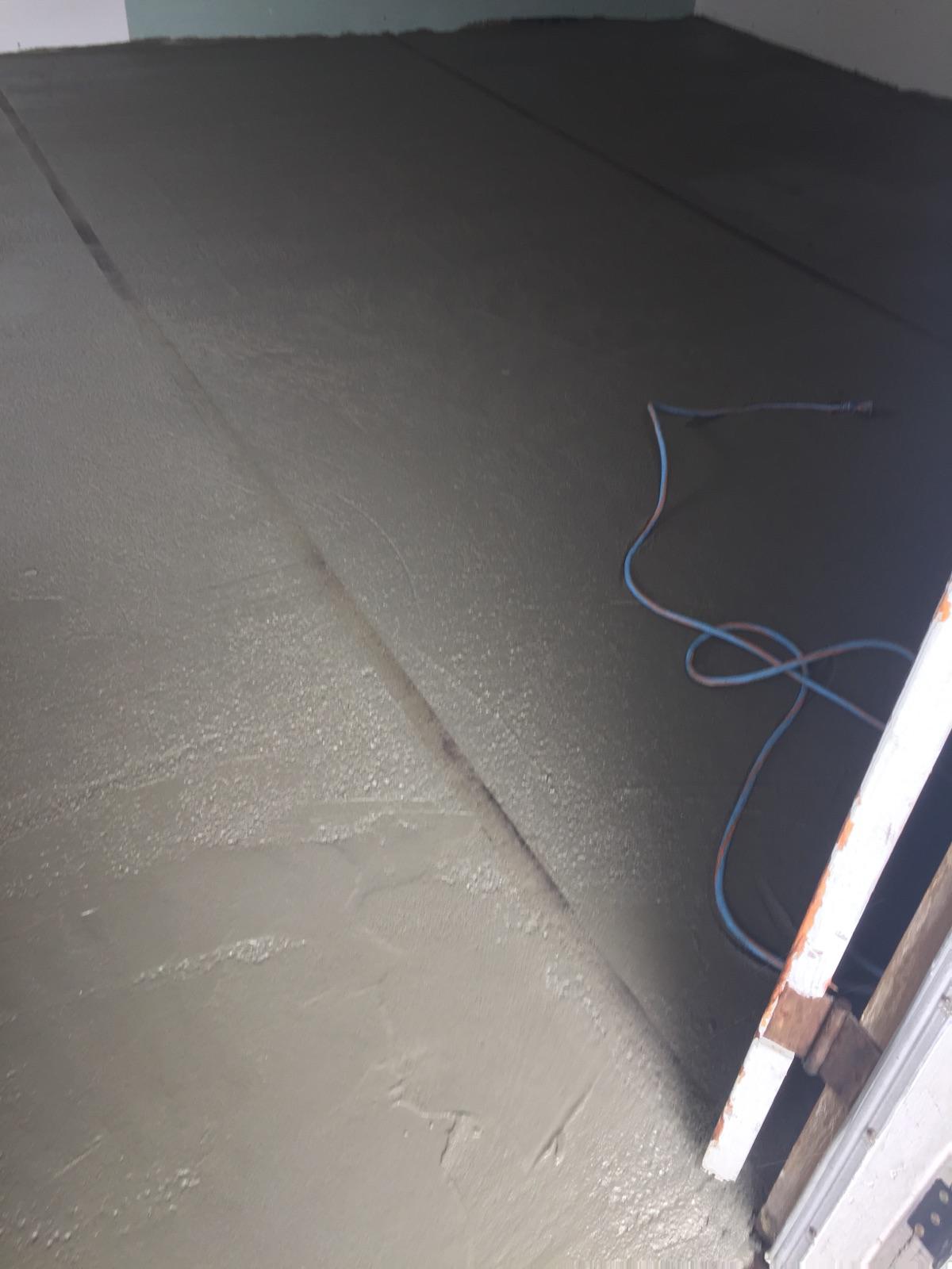 A wire is laying on the floor of an unfinished room.