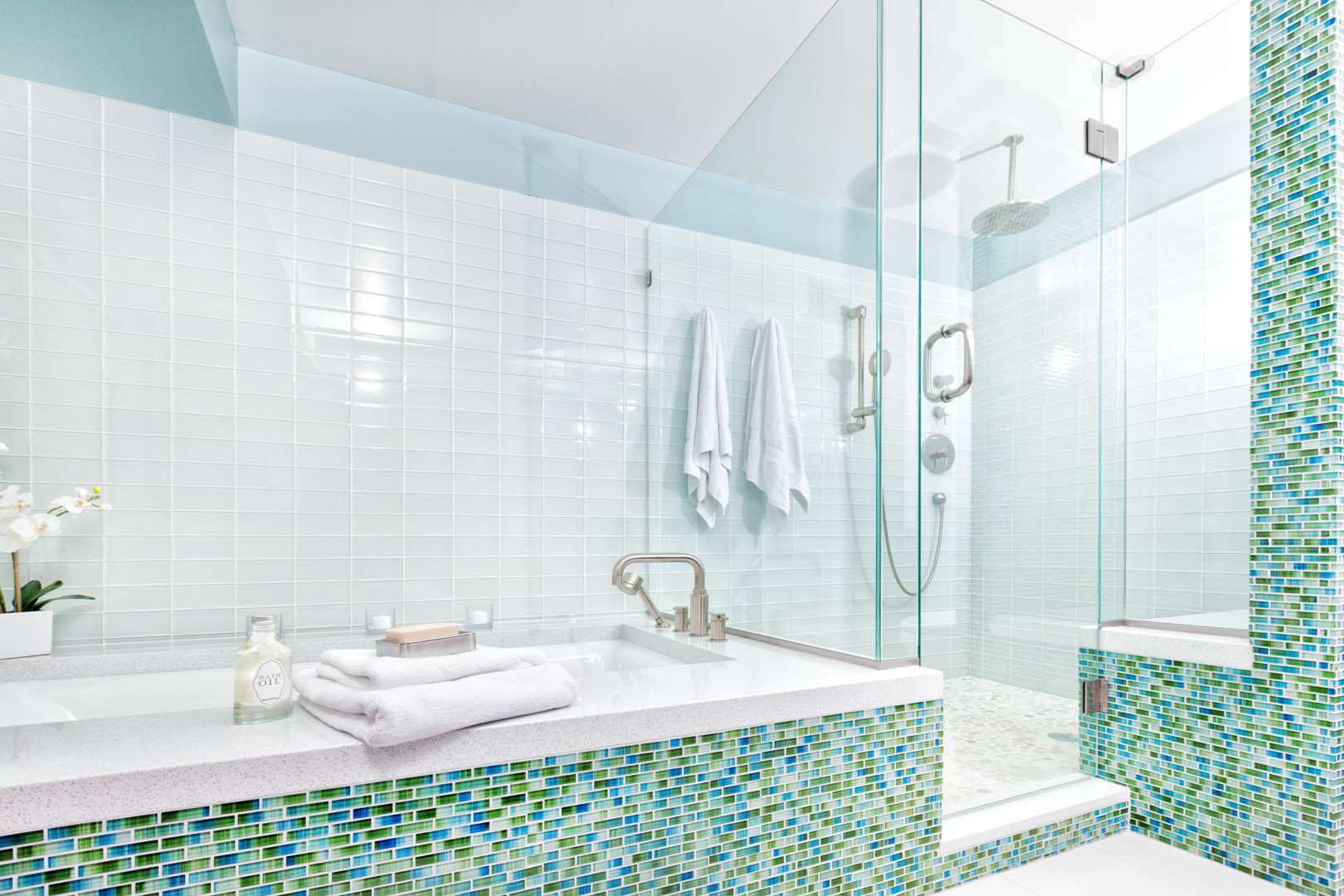A bathroom with a glass shower and tiled walls.