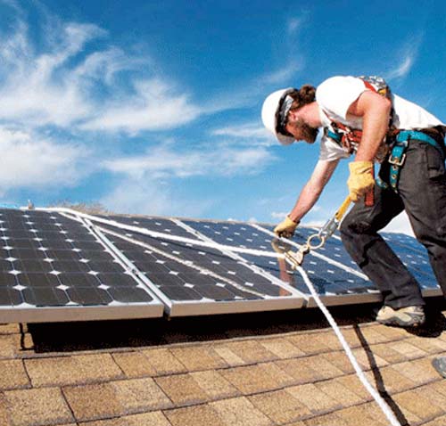 A man is cleaning the roof of a solar panel.