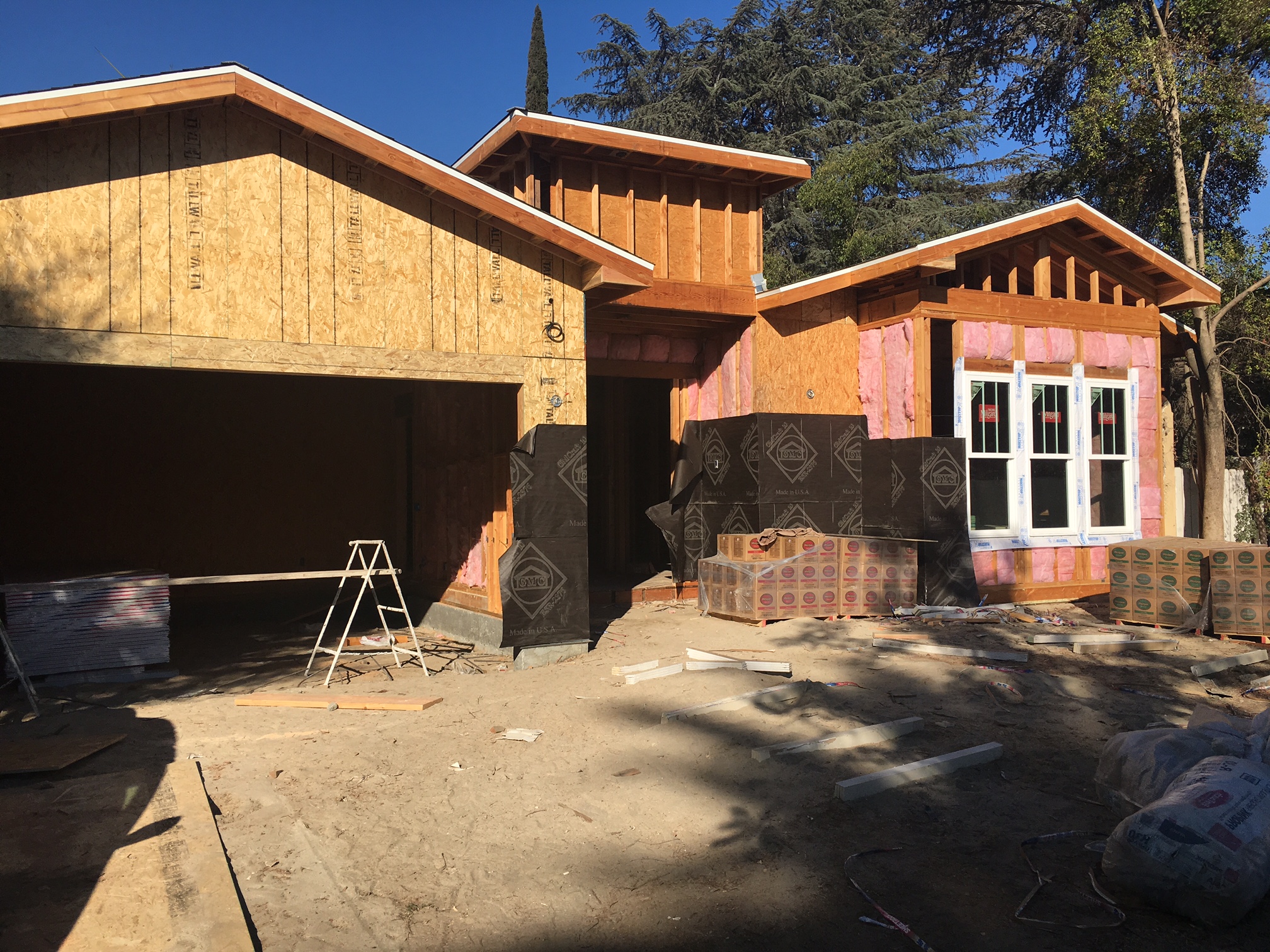 A house being built with wood siding and a garage door.